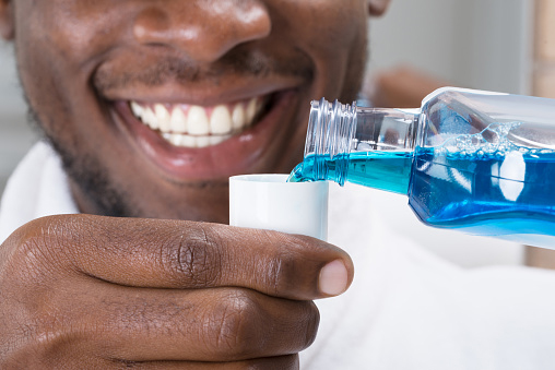 African American man pouring mouthwash after visit to Riverwind Dental in Richmond, VA