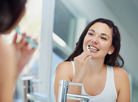 Woman brushing teeth before making an appointment at Riverwind Dental in Richmond, VA