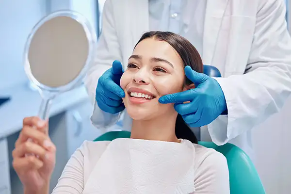 Smiling dental patient looking into mirror after a cleaning at Riverwind Dental in Richmond, VA Smiling dental patient looking into mirror after a cleaning at Riverwind Dental in Richmond, VA