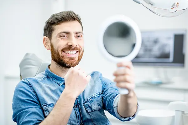 Bearded patient checking out his handsome smile in a mirror while sitting in a dental chair at Riverwind Dental in Richmond, VA Bearded patient checking out his handsome smile in a mirror while sitting in a dental chair at Riverwind Dental in Richmond, VA
