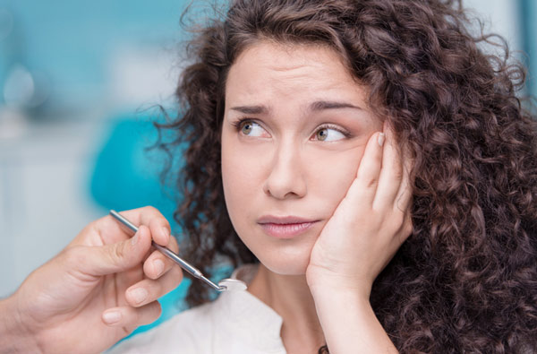 Woman at Riverwind Dental in Richmond, VA holding cheek due to tooth ache