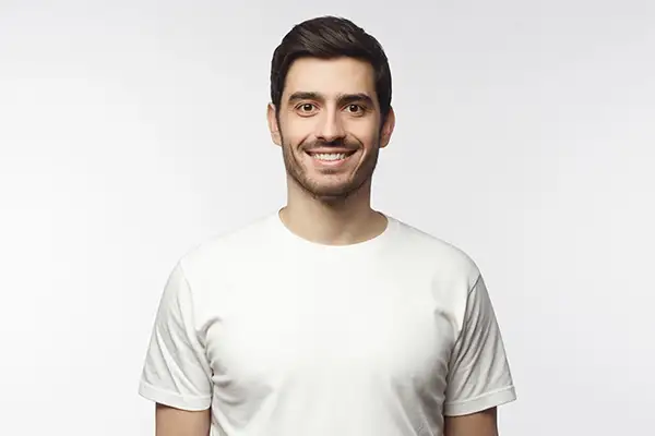A smiling man with porcelain crowns wearing a white t-shirt at Riverwind Dental in Henrico, VA