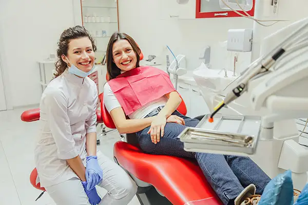 A dentist smiling brightly with her seated patient at Riverwind Dental in Henrico, VA