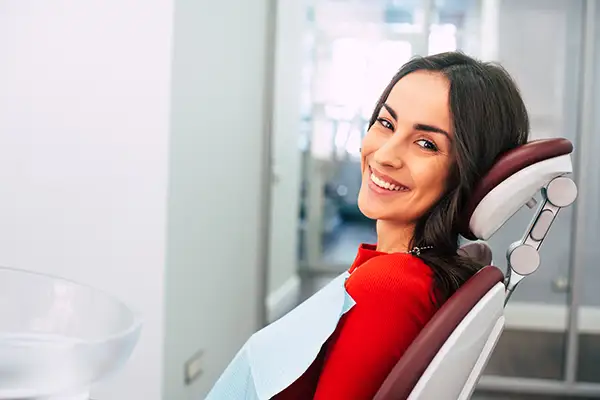 A woman smiling brightly in the dentist chair with a bib on at Riverwind Dental in Henrico, VA