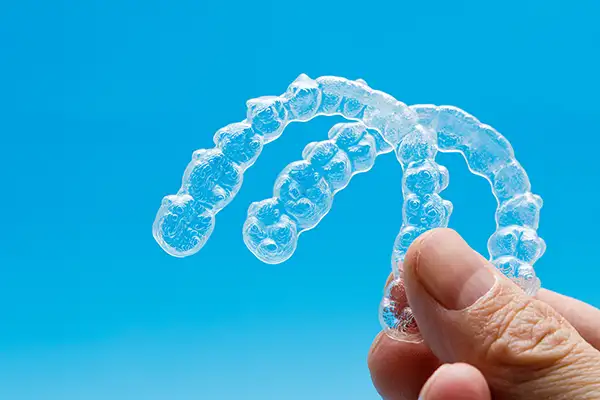 Close-up of a hand holding upper and lower Invisalign clear aligner trays at Riverwind Dental in Richmond, VA