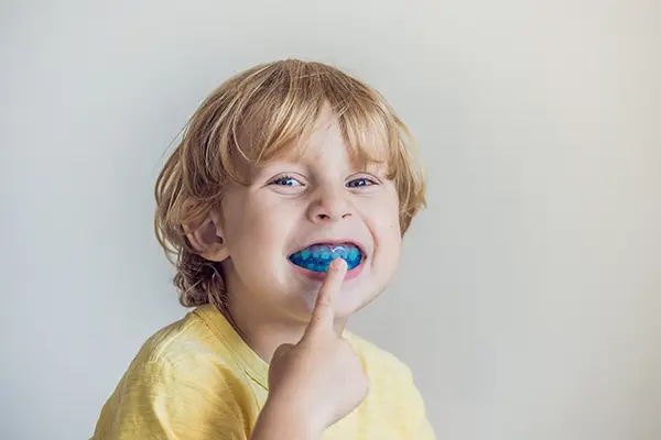 A young boy showing how his sports guard protects his teeth from injury at Riverwind Dental in Richmond, VA