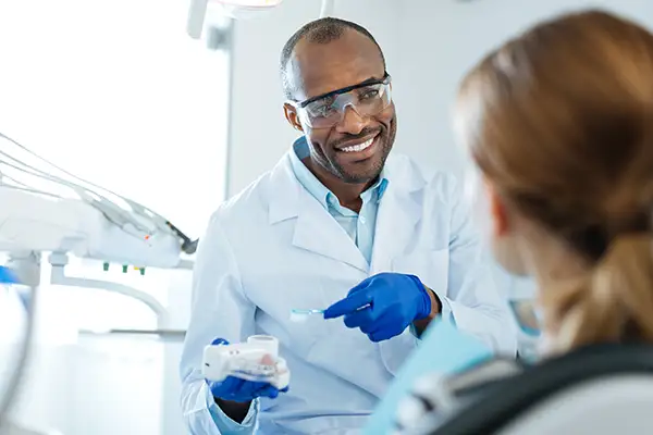 Smiling dentist explaining brushing tips to a patient using a dental model at Riverwind Dental in Henrico, VA