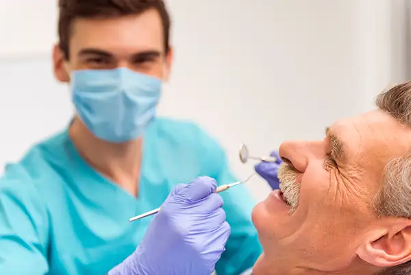 A dentist examining the dental implants of a happy and comfortable senior patient at Riverwind Dental in Henrico, VA