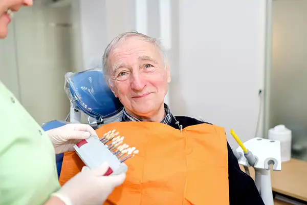 A dentist consults a shade match with a senior patient during an implant consultation at Riverwind Dental in Henrico, VA